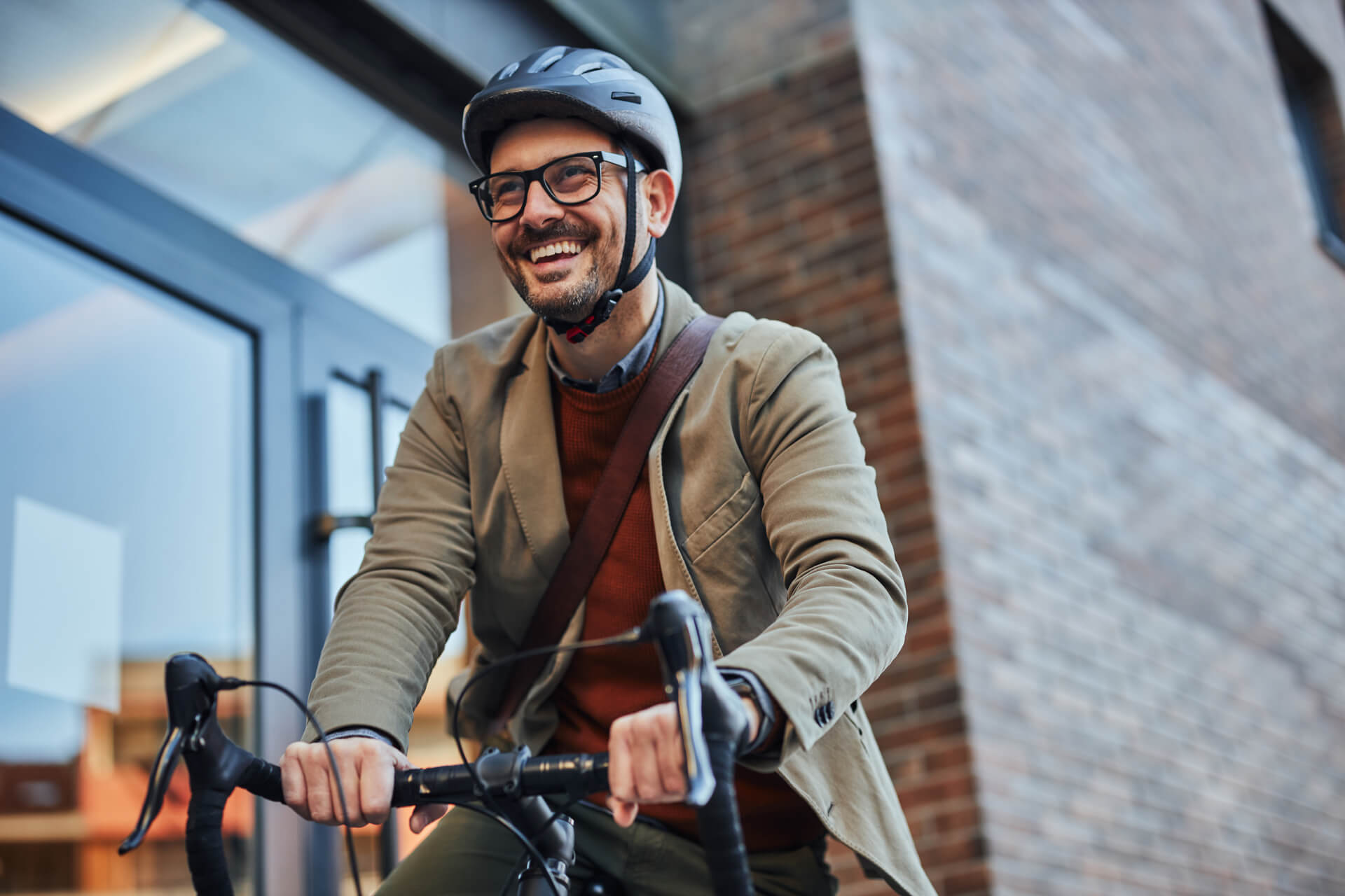 Man in his 30s wearing a business suit and a helmet. Worker riding a bike to get to his workplace